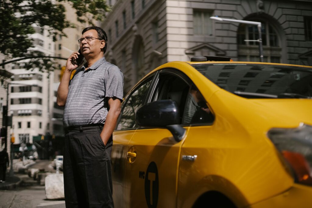 Ethnic male in eyeglasses holding hand in pocket while standing on street and talking on phone